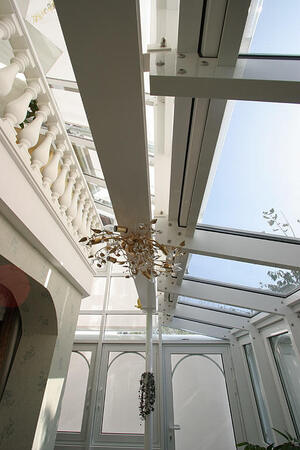 Moderner Wintergarten mit Glasdach, verzierten Elementen und heller Innenarchitektur.