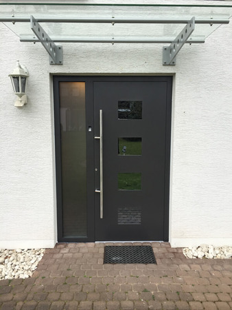 Moderne Haustür aus Aluminium mit Glaselementen und Vordach für Hauseingang.